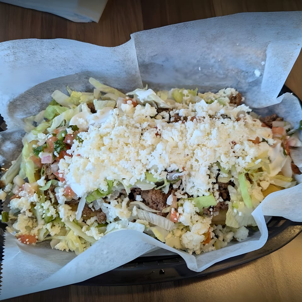 Sabor's Mexican nachos with ground beef, lettuce, pico de gallo, sour cream, and crumbled cheese.